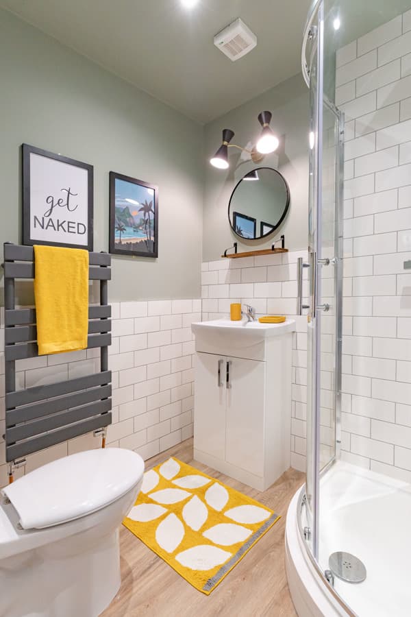 A modern Bunked bathroom with a walk-in shower and yellow accents