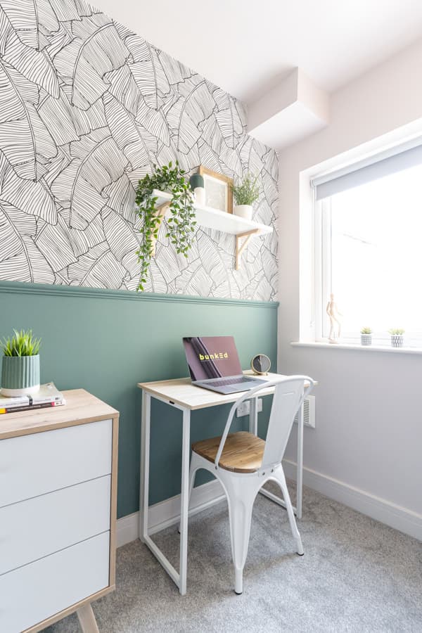 A bright Bunked student bedroom with a double bed and desk
